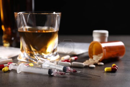 Photo for Alcohol and drug addiction. Syringes, whiskey in glass and pills on grey table, closeup - Royalty Free Image