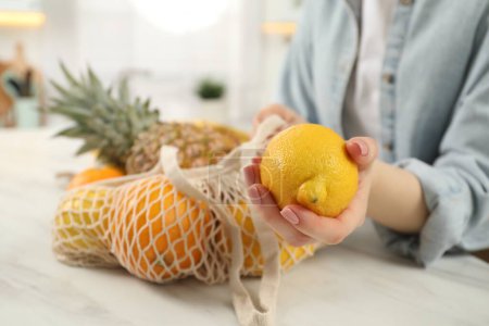 Téléchargez les photos : Femme avec sac à ficelle de fruits frais et citron à la table lumineuse, gros plan - en image libre de droit