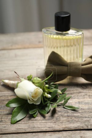 Téléchargez les photos : Des mariages. boutonnière élégante, parfum et noeud papillon sur table en bois, gros plan - en image libre de droit