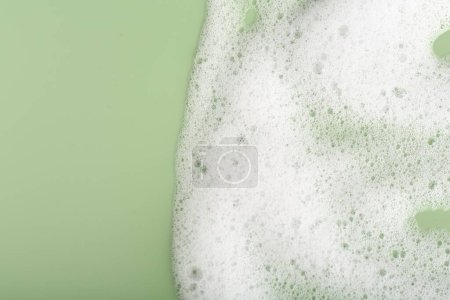 Mousse blanche moelleuse sur fond vert, vue de dessus. Espace pour le texte