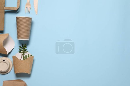 Flat lay composition with eco friendly food packagings and twigs on light blue background. Space for text