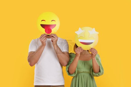 Foto de Personas cubriendo caras con emoticonos sobre fondo amarillo - Imagen libre de derechos