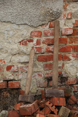 Sledgehammers on pile of bricks near wall outdoors