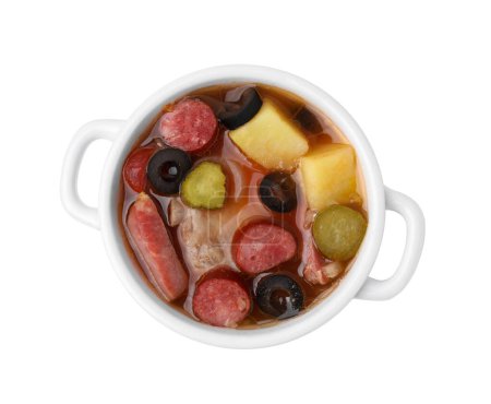 Meat solyanka soup with thin dry smoked sausages in pot isolated on white, top view