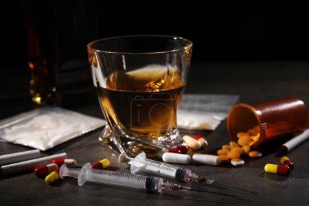 Photo for Alcohol and drug addiction. Whiskey in glass, syringes, pills, pills and cocaine on grey table - Royalty Free Image