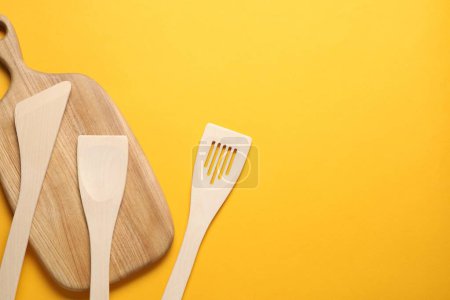 Téléchargez les photos : Différentes spatules en bois et planche sur fond orange, pose plate. Espace pour le texte - en image libre de droit