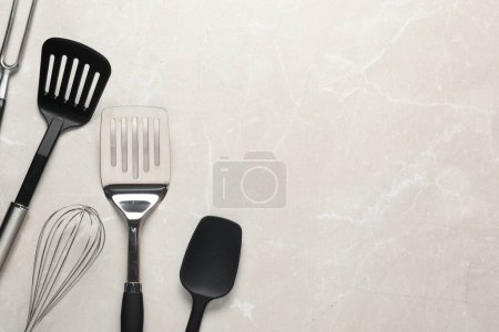 Téléchargez les photos : Différentes spatules, fouet et fourchette à sculpter sur une table en marbre clair, pose plate. Espace pour le texte - en image libre de droit
