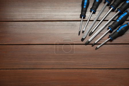 Set of screwdrivers on wooden table, top view. Space for text