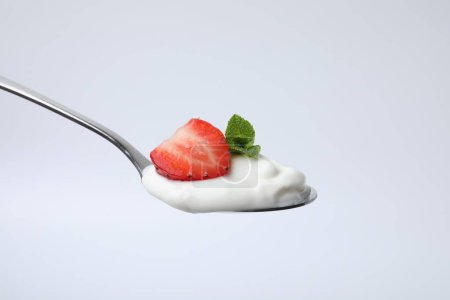 Cuchara con yogur, fresa y menta aislada en blanco
