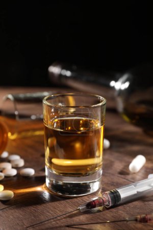 Photo for Alcohol and drug addiction. Whiskey in glass, syringes and pills on wooden table - Royalty Free Image