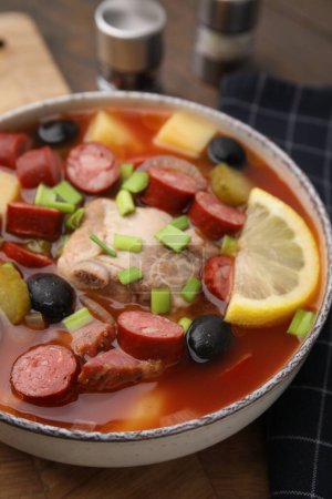 Téléchargez les photos : Soupe de viande solyanka avec de fines saucisses fumées sèches dans un bol sur une planche de bois, gros plan - en image libre de droit