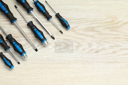 Set of screwdrivers on white wooden table, top view. Space for text