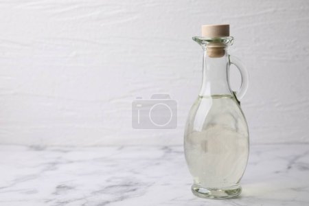 Foto de Vinagre en jarra de vidrio sobre mesa de mármol blanco, espacio para texto - Imagen libre de derechos