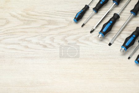 Juego de destornilladores en mesa de madera blanca, vista superior. Espacio para texto