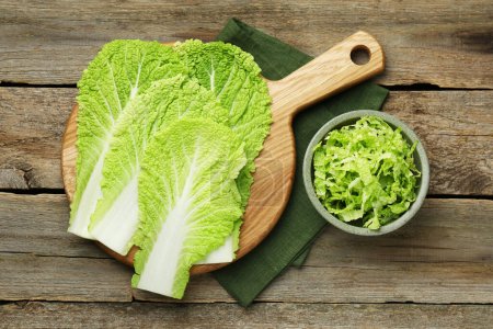 Cut fresh Chinese cabbage and leaves on wooden table, top view