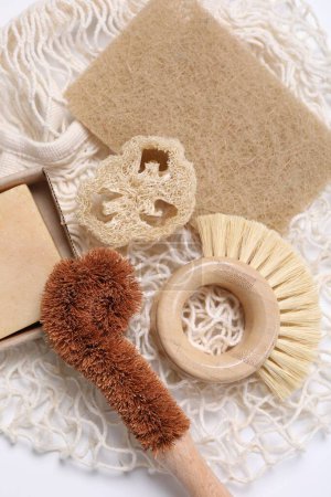 Téléchargez les photos : Brosses de nettoyage, éponge, loofah et barre de savon sur table blanche, vue de dessus - en image libre de droit