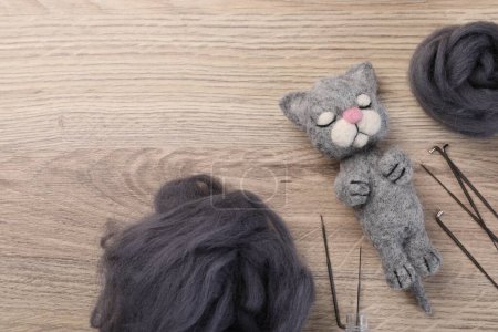 Gefilzte Katze, Wolle und Werkzeug auf Holztisch, flach gelegt. Raum für Text