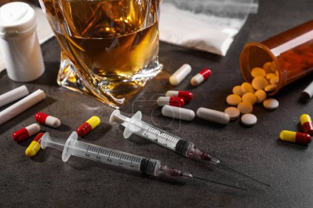 Photo for Alcohol and drug addiction. Whiskey in glass, syringes, pills and cigarettes on grey table, closeup - Royalty Free Image