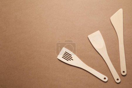 Téléchargez les photos : Différentes spatules en bois sur fond brun, plat. Espace pour le texte - en image libre de droit