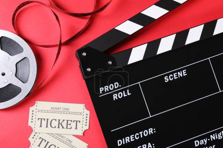 Clapperboard, billets de cinéma et bobine de film sur fond rouge, plat