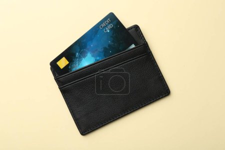 Téléchargez les photos : Porte-cartes en cuir avec carte de crédit sur fond beige, vue de dessus - en image libre de droit