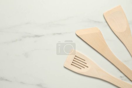 Téléchargez les photos : Différentes spatules en bois sur table en marbre blanc, plat. Espace pour le texte - en image libre de droit