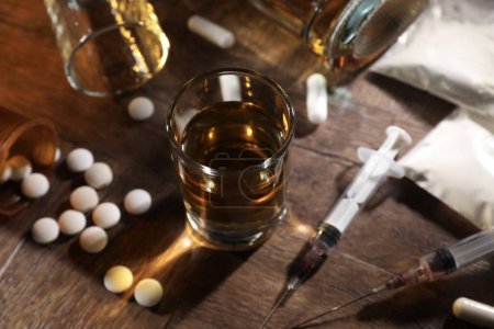 Photo for Alcohol and drug addiction. Whiskey in glass, syringes, pills and cocaine on wooden table, closeup - Royalty Free Image