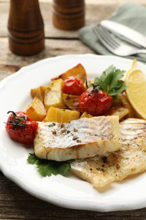 Foto de Sabroso bacalao cocido con verduras servidas sobre mesa de madera, primer plano - Imagen libre de derechos