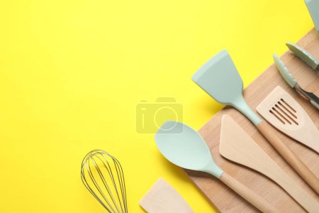 Téléchargez les photos : Différentes spatules, fouetter et pinces sur fond jaune, plat. Espace pour le texte - en image libre de droit