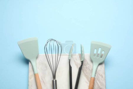 Téléchargez les photos : Différentes spatules, fouetter et pinces sur fond bleu clair, plat. Espace pour le texte - en image libre de droit
