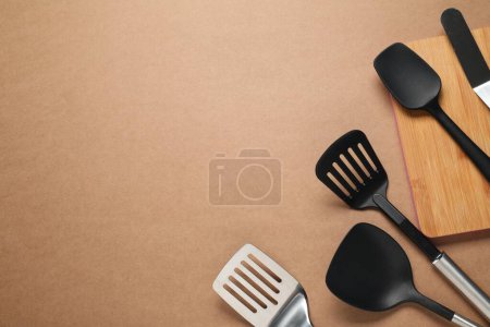 Téléchargez les photos : Différentes spatules sur fond brun, plat. Espace pour le texte - en image libre de droit