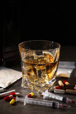 Photo for Alcohol and drug addiction. Whiskey in glass, syringes, pills, pills and cocaine on grey table - Royalty Free Image