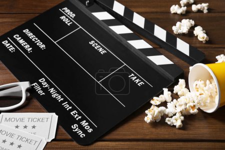 Clapperboard, movie tickets, 3D glasses and popcorn on wooden table, closeup
