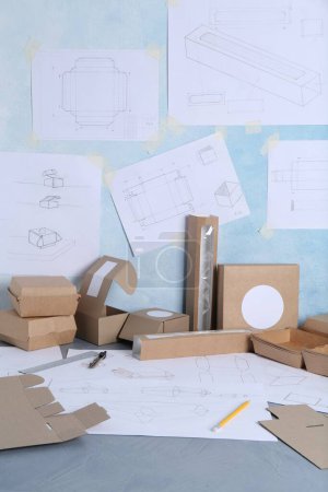 Photo for Creating packaging design. Drawings, boxes and stationery on blue textured table, closeup - Royalty Free Image