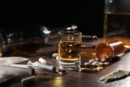 Photo for Alcohol and drug addiction. Whiskey in glass, syringes, pills and cocaine on wooden table - Royalty Free Image