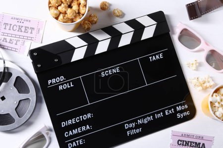 Flat lay composition with clapperboard and popcorn on white wooden table