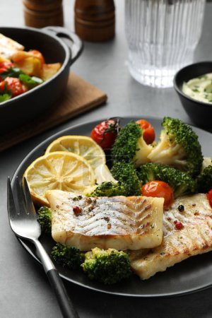 Foto de Sabroso bacalao cocido con verduras servido sobre mesa gris - Imagen libre de derechos
