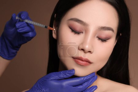 Photo for Woman getting facial injection on brown background - Royalty Free Image