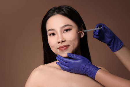Photo for Woman getting facial injection on brown background - Royalty Free Image