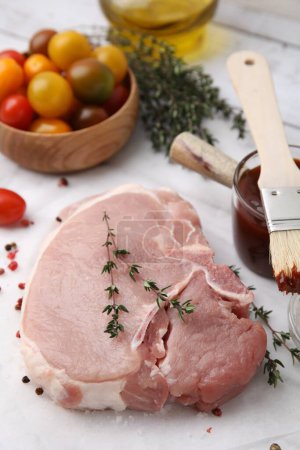 Viande crue, thym, épices et marinade sur table blanche, gros plan