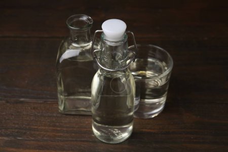 Foto de Vinagre en botellas y vidrio sobre mesa de madera - Imagen libre de derechos