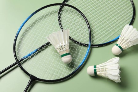 Photo for Feather badminton shuttlecocks and rackets on green background, above view - Royalty Free Image