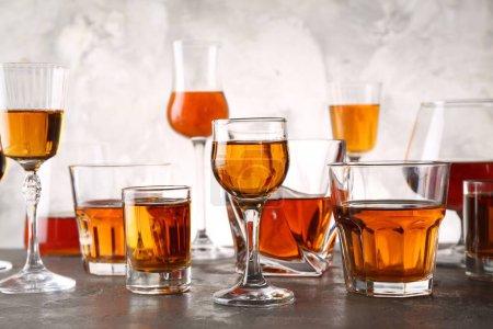 Different delicious liqueurs in glasses on grey table
