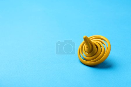 One yellow spinning top on light blue background, space for text