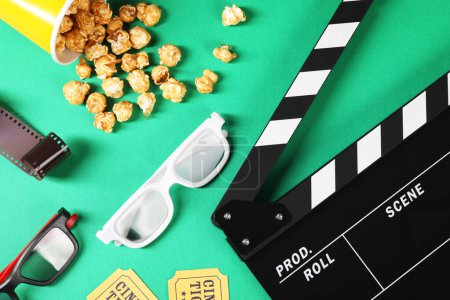 Flat lay composition with clapperboard, movie tickets and 3D glasses on green background