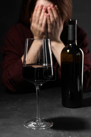 Téléchargez les photos : L'alcoolisme. Femme couvrant son visage à la table sombre texturée, se concentrer sur un verre de vin rouge - en image libre de droit