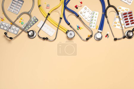 Photo for Stethoscopes and pills on beige background, flat lay. Space for text - Royalty Free Image