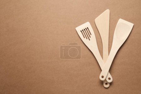 Téléchargez les photos : Différentes spatules en bois sur fond brun, plat. Espace pour le texte - en image libre de droit