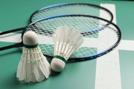 Photo for Feather badminton shuttlecocks and rackets on green table, closeup - Royalty Free Image