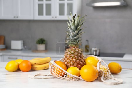 Téléchargez les photos : Sac à cordes avec fruits frais sur table lumineuse dans la cuisine - en image libre de droit